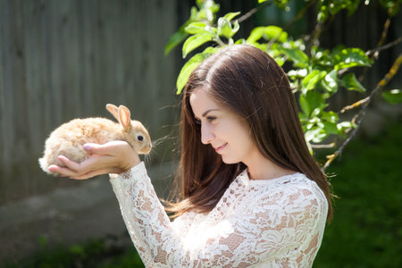 Portrait of woman with adorable rabbit in a summer garden. Easter conceptの写真素材
