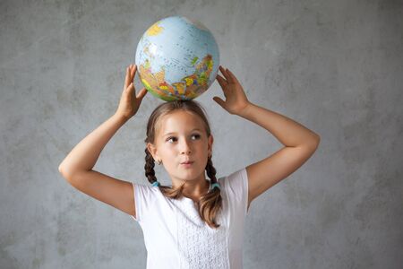 Portrait of a happy school girl with pigtails in a uniform with a globe. Back to school. distance...