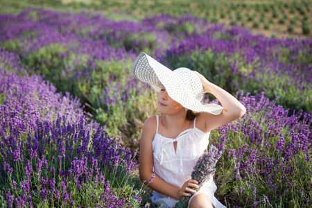 Cute girl in a white dress having fun in a lavender fieldの写真素材