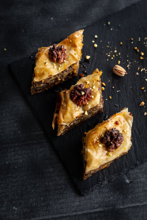 Homemade baklava with pistachios and walnuts and honey and orange syrup served in a black plate. Turkish culture Turkish cuisine. Place for textの写真素材