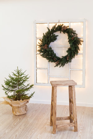 Christmas green wreath with cones on the window in a holiday studioの写真素材