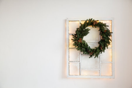 Christmas green wreath with cones on the window in a holiday studioの写真素材
