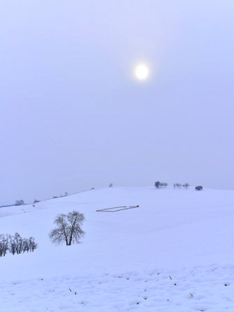 Mountain snow landscape on a foggy winter day. Sun faded by the fog. Cold weather.の写真素材