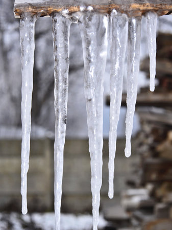 Icicles hanging from the roof of a wooden house in winter. Transylvania.の写真素材