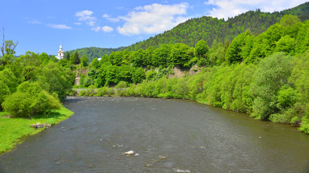 Mountain landscape with a small river and a church in the center. Mures river, Transylvania.の写真素材