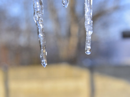 Icicles hanging from the roof of a house in winter.の写真素材