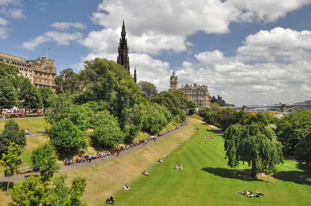 Edingburgh, Scotland - July 7, 2010: East Princess Street Gardens in Edinburgh/Scotland with view to the Scott Monument, the Balmoral Hotel and the North Bridge. In the park people are relaxing in the sun.のeditorial素材