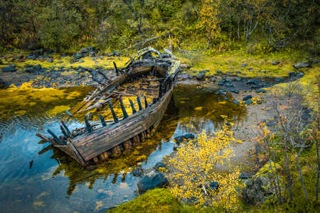 Stranded wooden shipwreck at Austnesfjorden in bright autmun colors, Lofoten island, Norwayの写真素材