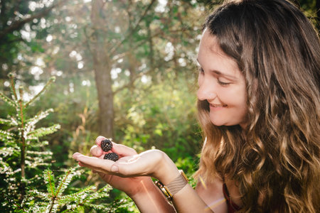 Young smiling woman picking blackberries in the woodsの写真素材