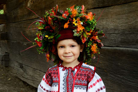 little girl in national dress and a wreath of flowers on a background of authentic Ukrainian house. Ethnographic vestival summer, Ukraineの写真素材
