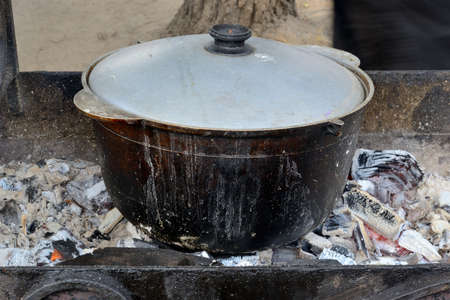 outdoors in a saucepan over an open fire preparing foodの写真素材