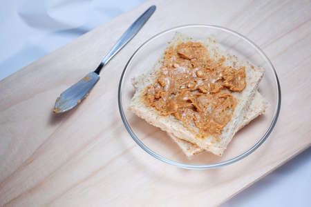 A macro  of peanut butter being spread on whole wheat breadの写真素材