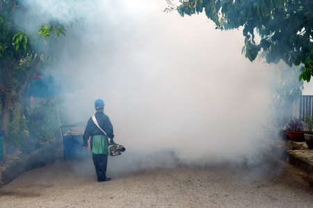 Worker fogging residential area with insecticides to kill aedes mosquito breeding ground, carrier of dengue virusの写真素材
