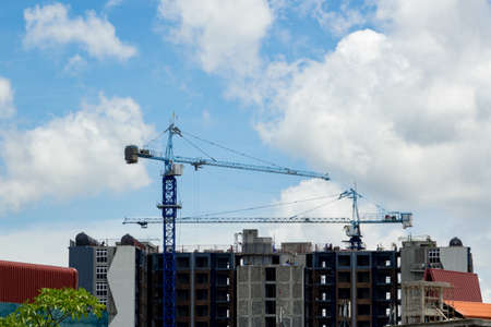 Crane and building construction site against blue skyの写真素材