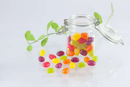 Jelly Beans spilt from Glass Jar with Open Lid and Metal Claspの写真素材