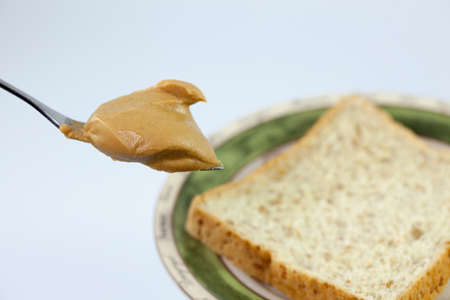 Creamy peanut butter in a spoon and breadの写真素材