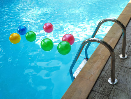 Pool fun concept with an inflatable plastic beach ball floating in cool crystal clear reflective waterの写真素材