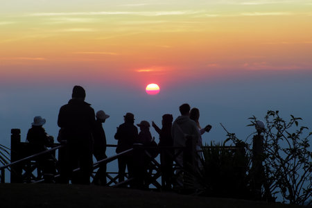 asians travel relax in the holiday.People stand looking at the sun in the morning. Stand up for sunrise on the Moutainの写真素材