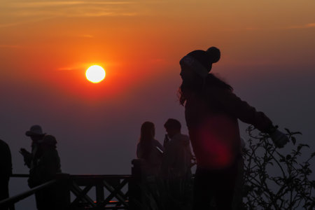 asians travel relax in the holiday.People stand looking at the sun in the morning. Stand up for sunrise on the Moutainの写真素材