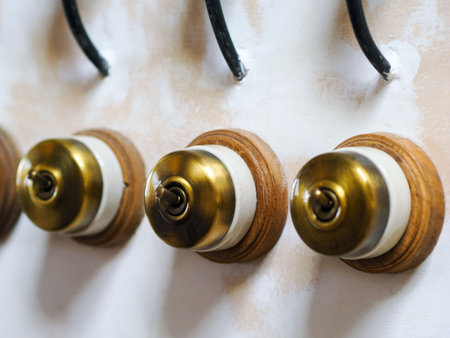 Retro style brass power switches on white wall. Brass vintage switch on interior wall.