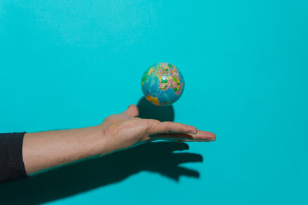 Hand throwing planet earth ball with blue background and copy space for text.の写真素材