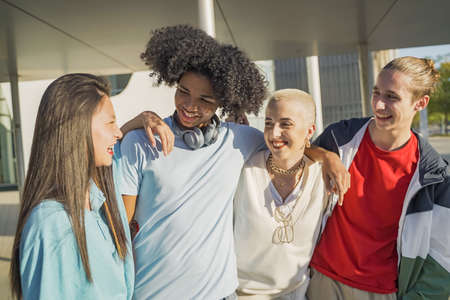 Group of multiethnic young students walking laughing on the modern university campus during a sunny day.の写真素材