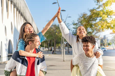 Multiethnic group of young happy friends walking down the street hitting high five.の写真素材