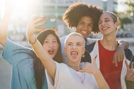 Multiethnic teenage friends taking a selfie group photo and laughing happy in the campus. Technology lifestyle concept.の写真素材