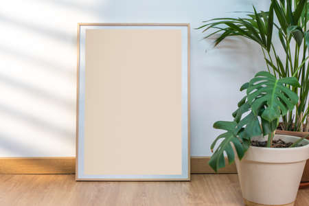 Boho wood frame vertical monograph mockup on clean white walls, plants and sun rays.の写真素材