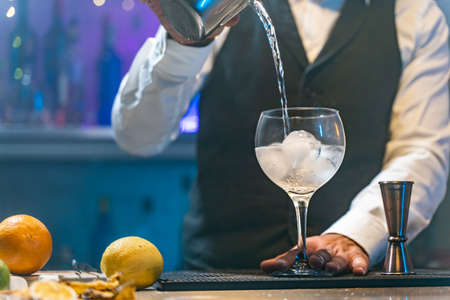 Barman making cocktail in night club adding ingredients and creating expert drinks on bar counter copy space.の写真素材