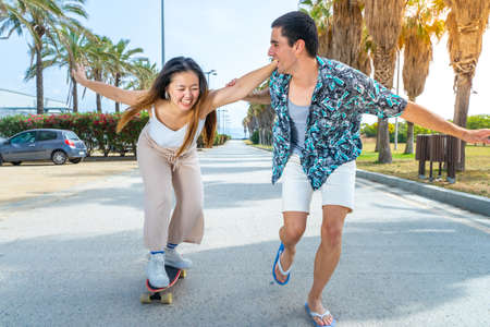 Young diverse couple with skateboard and longboard having fun outdoors.の写真素材