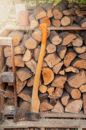 Axe in front of a stack of wood in a woodshed. Natural background.