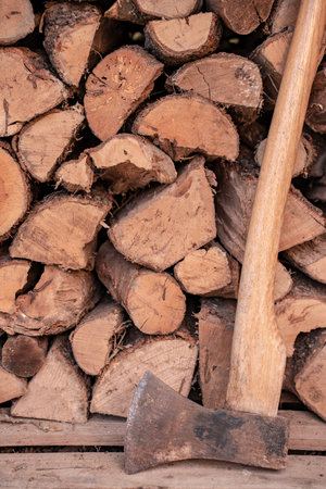 Axe in front of a stack of wood in a woodshed. Natural background with copy space.