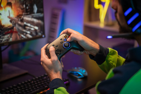 Gamer hands playing with joystick on green screen in trendy and stylish room with neon light