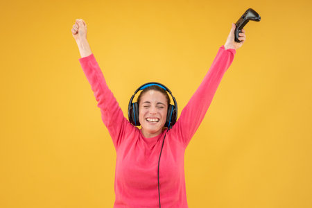 Beautiful woman playing games wearing headphones standing isolated yellow background.