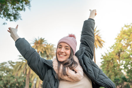 Portrait of a joyful woman smiling at camera with raised arms. Traveler girl enjoying freedom.の写真素材