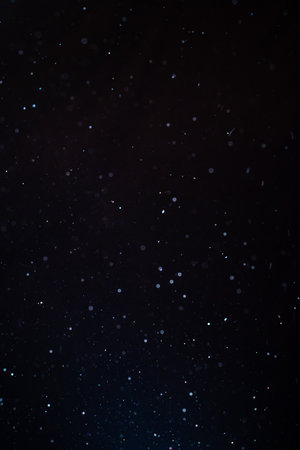 Natural organic dust particles floating on a sunbeam on black background.の写真素材