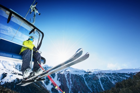 Skier siting on ski-lift - lift at sunny day and mountain Skier siting on ski-lift - lift at sunny day and mountain