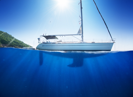 Amazing sunlight seaview to sailboat in tropical sea with deep blue underneath splitted by waterlineの写真素材