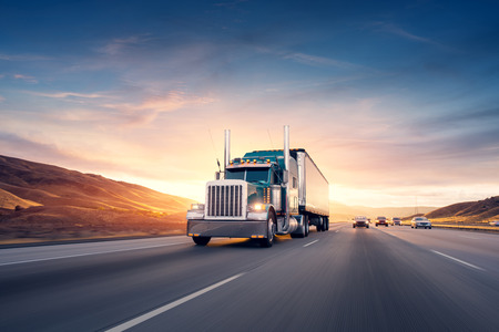 American style truck on freeway pulling load.