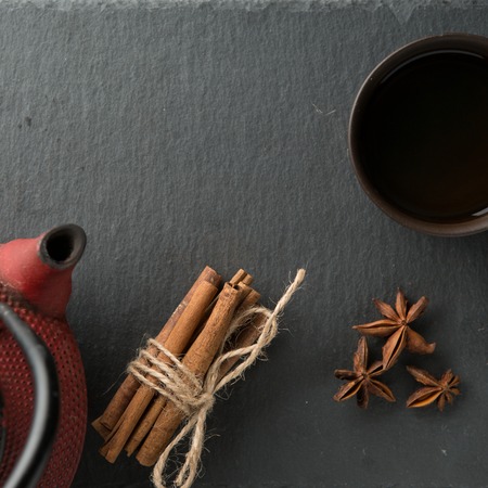 Iron teapot and traditional ceramic cup of tea with bunch of cinnamon sticks and star anise. Asian style.の写真素材