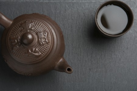 traditional clay teapot with clay cup full of green tea on black slate backgroundの写真素材