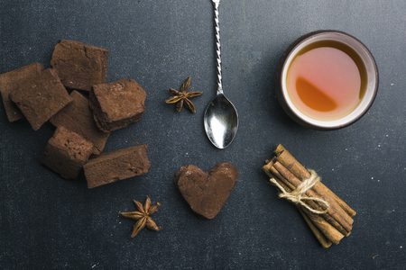 Tea composition with cinnamon , anis chocolate marshmallow and red iron teapot on dark stone background. Horizontal, top viewの写真素材