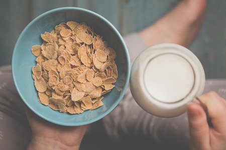 Woman hold sky blue colored bowl of tasty cereal corn flakes