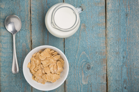 Corn flakes in a white bowl and jug of milk on blue old wooden background healty quick breakfastの写真素材