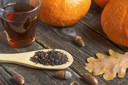 Autumn background for Thanksgiving or halloween concept on a wooden table with a pumpkins, a glass cup of tea and acornsの写真素材