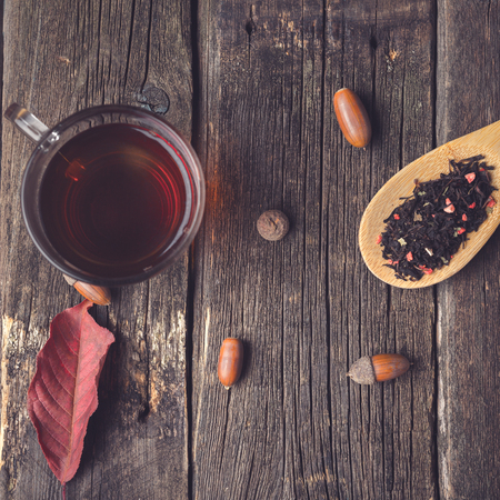 Tea with spices and spoonful of tea, acorns, oak leaf on a wooden background, rustic style, autumn composition postcard, copy spaceの写真素材