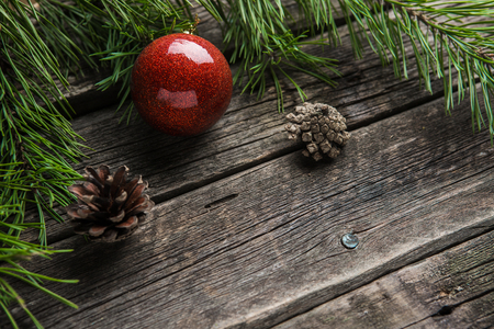 evergreen fir twigs with shiny red baubles and pine cones on old wooden backgroundの写真素材