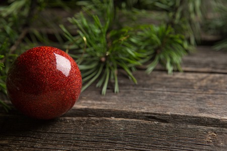 Christmas greeting card frame with place for your text. Decorations of green fir branches, red glass Christmas balls, against a background of brown old worn wooden boardsの写真素材