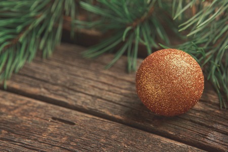 Gold Christmas ball with pine or fir branch on old worn wooden surfaceの写真素材